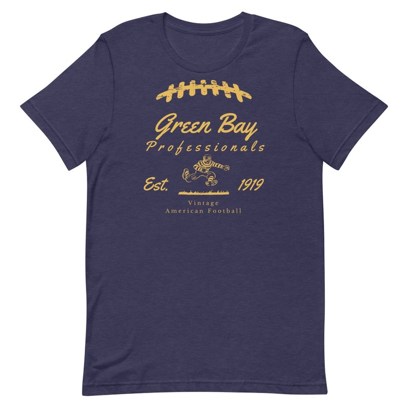 K&ouml;nnte beinhalten: Ein marineblaues T-Shirt mit einer Vintage-Grafik eines laufenden Footballspielers mit dem Text "Green Bay Professionals Est. 1919 Vintage American Football" in Gold.