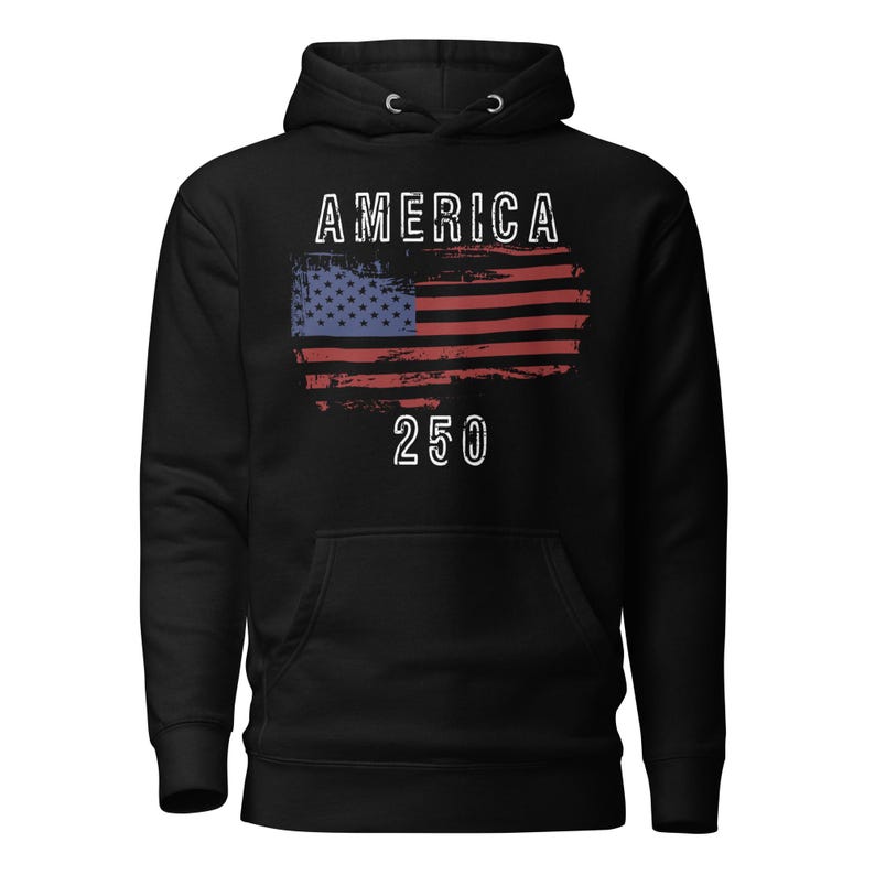 May include: Black colored hoodie featuring a America 250 with a distressed American Flag. The hoodie has a kangaroo pocket and a drawstring hood. The graphic is detailed with a distressed effect.
