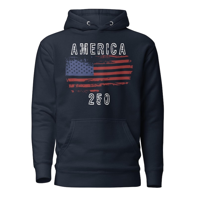 May include: Navy Blue colored hoodie featuring a America 250 with a distressed American Flag. The hoodie has a kangaroo pocket and a drawstring hood. The graphic is detailed with a distressed effect.