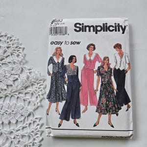 Peut inclure: Une pochette de patron de couture Simplicity easy to sew illustrant quatre tenues différentes, dont une robe à fleurs, une combinaison sombre, un ensemble rose et une jupe à fleurs avec un haut. L'enveloppe en papier blanc porte la marque.