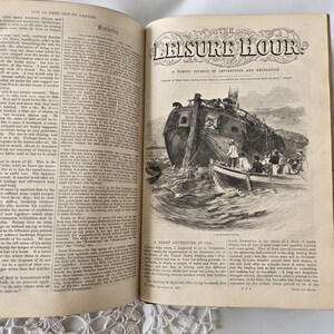 Op de afbeelding: Een open oud boek met tekst en een illustratie van een schip en kleine boten. De titel "The Leisure Hour" is bovenaan zichtbaar. De pagina is gevuld met tekstkolommen, kenmerkend voor een familieblad.