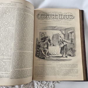 Op de afbeelding: Een open oud boek met tekst en illustraties. De rechterpagina toont een gedetailleerde zwart-wit illustratie van een sc&egrave;ne met figuren in een kamer. De titel "THE LEISURE HOUR" is bovenaan zichtbaar.
