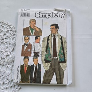 Peut inclure: Une pochette de patron de couture Simplicity présentant des illustrations de divers styles de vêtements masculins formels, incluant blazers, gilets et écharpes. L'enveloppe en papier blanc affiche la marque Simplicity et le numéro 8785.