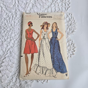 May include: Vintage Vogue Patterns sewing pattern with illustrations of three dresses: a red knee-length dress, a white polka-dot maxi dress, and a blue floral maxi dress. The pattern is size 12.
