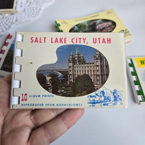 May include: A vintage Salt Lake City, Utah album print booklet. The cover features a color image of a large building with spires, a lake, and the text "SALT LAKE CITY, UTAH". The booklet contains 10 album prints.
