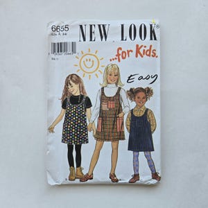May include: A sewing pattern for a girl's jumper dress. The pattern is called "New Look...for Kids." and is for sizes 3-8. The pattern shows three different styles of the jumper dress, one with polka dots, one with plaid, and one with denim.