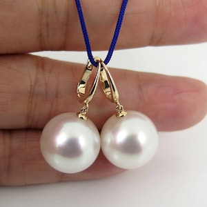 May include: A pair of white pearl earrings with gold hoops. The pearls are round and smooth.