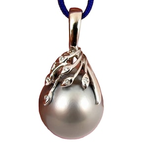 May include: A silver pendant featuring a large, gray, teardrop-shaped pearl. The pendant has a decorative silver design with small, clear gemstones and is suspended from a blue cord. The jewelry is set against a white background.