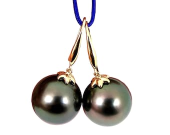 May include: A pair of black pearl earrings with gold accents. The earrings are suspended from gold hooks.
