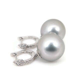May include: A pair of silver hoop earrings with a large, round, gray pearl dangling from each hoop. The hoops are decorated with small, clear diamonds.