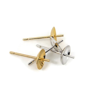 May include: Four earring posts with a gold and silver finish. The posts are designed to hold a pearl or other gemstone.