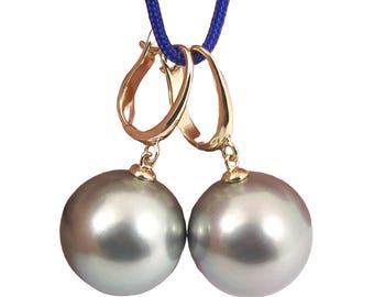May include: A pair of drop earrings featuring large, spherical, lustrous grey pearls suspended from polished gold-tone lever-back clasps. The earrings are hanging from a thin, vibrant blue cord, showcasing the smooth, reflective surface of the pearls.