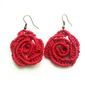 May include: A pair of red crocheted rose earrings with bronze hooks.