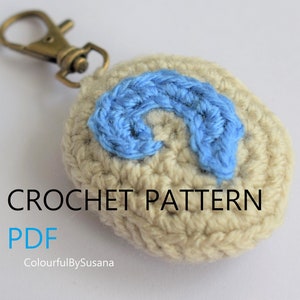 Może przedstawiać: Wzór na szydełku PDF do beżowego breloczka na szydełku z niebieską literą C na szydełku. Widoczny jest tekst "CROCHET PATTERN PDF" i "ColourfulBySusana".