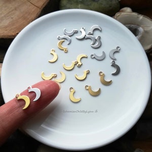 Könnte beinhalten: Ein weißer Teller mit einer Auswahl an goldenen und silbernen Halbmond-Anhängern. Die Anhänger sind zufällig auf dem Teller angeordnet. Die Anhänger sind klein und filigran und eignen sich perfekt, um Schmuck oder anderen Bastelarbeiten einen Hauch von Verspieltheit zu verleihen.