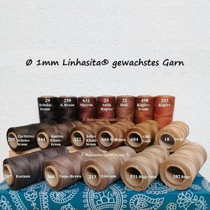Könnte beinhalten: Eine Sammlung von 1 mm Linhasita gewachstem Garn auf Spulen in verschiedenen Braun- und Beigetönen. Jede Spule ist mit einer Nummer und einem Farbnamen wie Zartbitter Schoko-braun, Kastanie und Stroh beschriftet und in Reihen angeordnet.