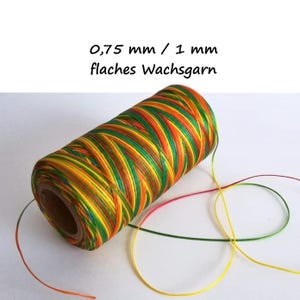 Könnte beinhalten: Eine Spule mit flachem Wachsgarn in einem lebendigen, mehrfarbigen Muster aus grünen, gelben und orangefarbenen Fäden. Der Text 0,75 mm / 1 mm flaches Wachsgarn ist über der Spule zu sehen und gibt die verfügbaren Garnstärken an.