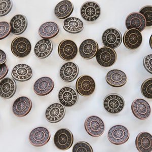 May include: A collection of round, metal clock face buttons with Roman numeral markings. The buttons are in various shades of gold, silver, and copper.
