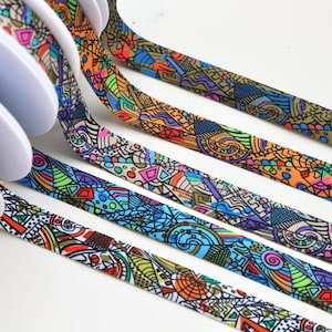 May include: Four spools of colourful patterned ribbon with a white background. The ribbon is made of a soft, flexible material and features a variety of abstract designs in bright colours.