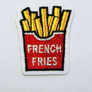 May include: An embroidered iron-on patch featuring a red and white box of french fries with the text "FRENCH FRIES" in white.