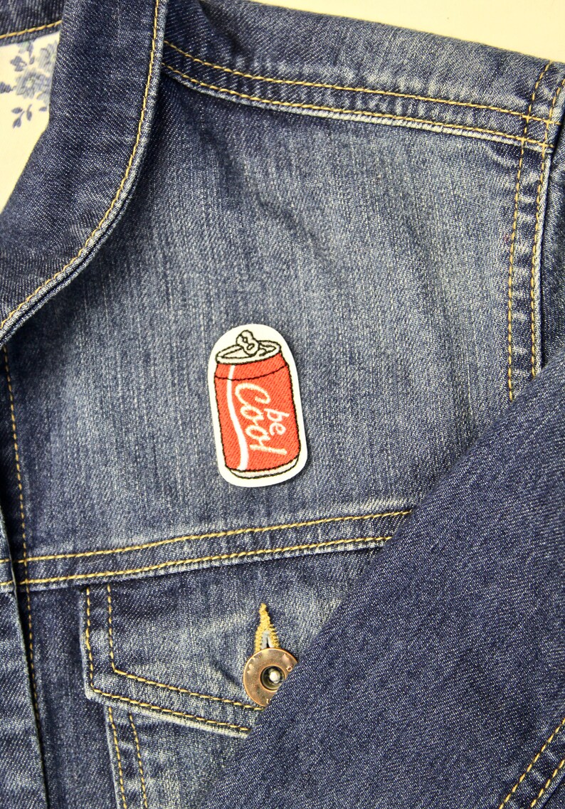May include: A denim jacket with a red and white embroidered patch of a soda can that says "Be Cool" on it.