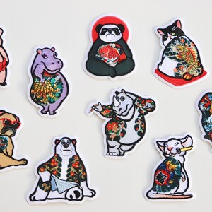 May include: Nine embroidered iron-on patches featuring various animals with traditional Japanese tattoos. The animals include a pig, a hippopotamus, a panda, a cat, a rhinoceros, a gorilla, a pug, a polar bear, and a rat.