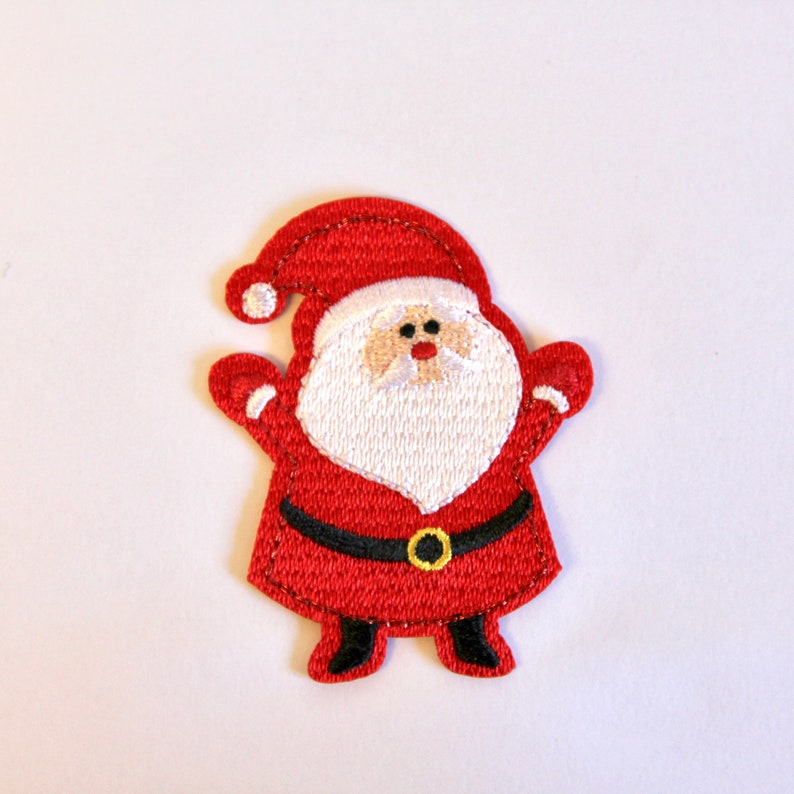 K&ouml;nnte beinhalten: Roter Filz-Weihnachtsanh&auml;nger mit einem Weihnachtsmann mit wei&szlig;em Bart und schwarzem G&uuml;rtel. Er tr&auml;gt einen roten Hut mit wei&szlig;em Rand.