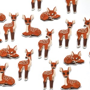 以下が含まれることがあります： 様々なポーズをとった子鹿が描かれた、茶色と白の刺繍入りアイロン接着パッチ16個セット。衣服、バッグ、その他の布製品に遊び心を取り入れるのに最適です。