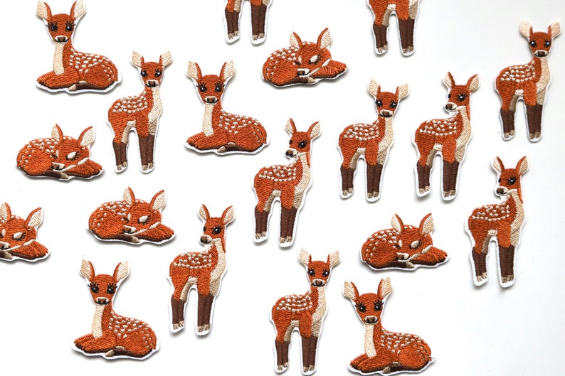 以下が含まれることがあります： 様々なポーズをとった子鹿が描かれた、茶色と白の刺繍入りアイロン接着パッチ16個セット。衣服、バッグ、その他の布製品に遊び心を取り入れるのに最適です。