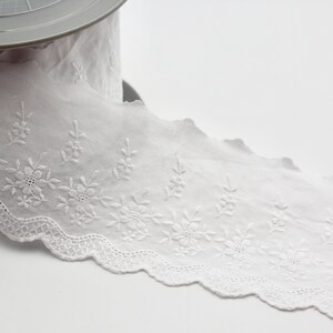 Peut inclure: Galon de dentelle en coton blanc avec un bord festonn&eacute; et une broderie florale d&eacute;licate.