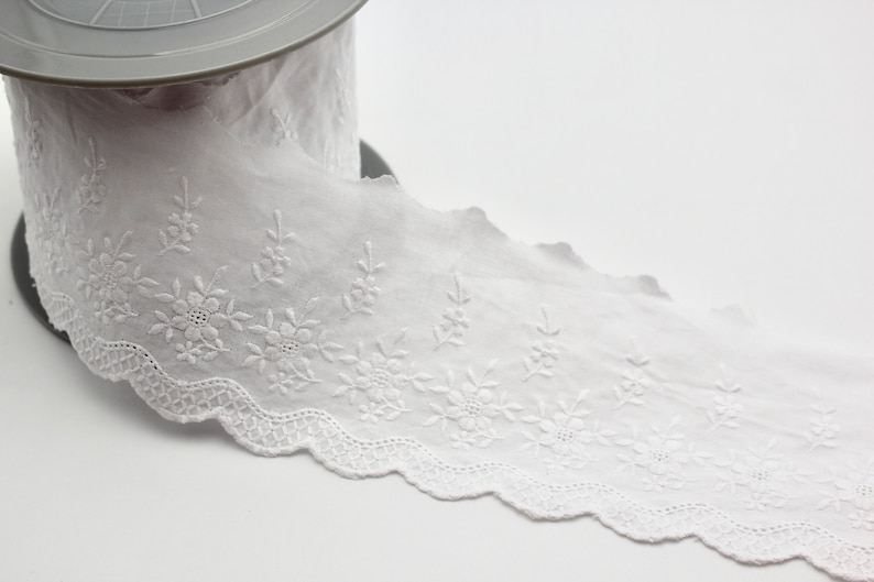 Peut inclure: Galon de dentelle en coton blanc avec un bord festonn&eacute; et une broderie florale d&eacute;licate.