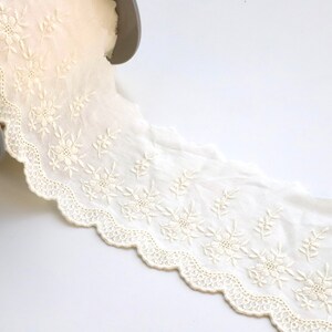 Peut inclure: Galon de dentelle en coton blanc avec un bord festonn&eacute; et une broderie florale d&eacute;licate.