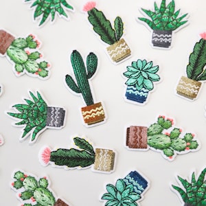 May include: A collection of 15 embroidered iron-on patches featuring various cacti and succulents in pots. The patches are colourful and feature a variety of green, pink, blue, and brown hues.