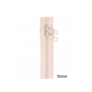 May include: A beige zipper with two pull tabs. The zipper is labeled "Stone".