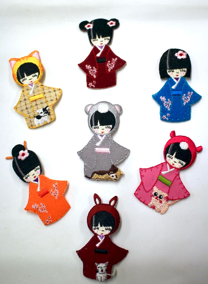 May include: Set of seven embroidered iron-on patches featuring adorable cartoon girls in various outfits and colors. Each patch includes a small animal companion.