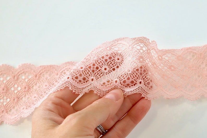 Puede incluir: Primer plano de un delicado encaje rosa con borde festoneado y un patr&oacute;n floral.