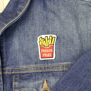 May include: A blue denim jacket with a red and yellow embroidered patch that says "French Fries".