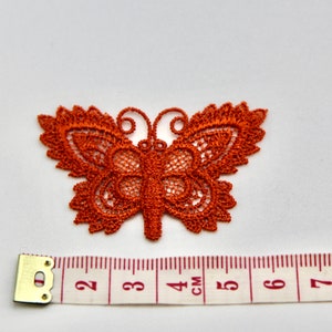 May include: A rust-colored lace butterfly applique measuring approximately 4 cm wide. The butterfly has intricate details and a delicate design.