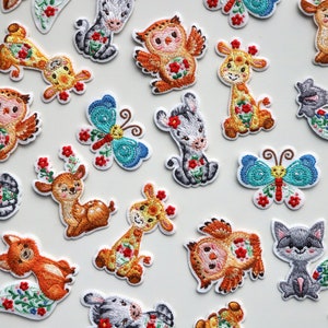 May include: A collection of embroidered iron-on patches featuring various animals and insects. The patches are colorful and feature a variety of designs, including a deer, a fox, an owl, a butterfly, and a giraffe. The patches are perfect for adding a touch of whimsy to clothing, bags, or other fabric items.