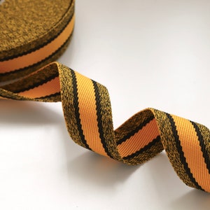 May include: A black and orange striped ribbon with a textured surface.