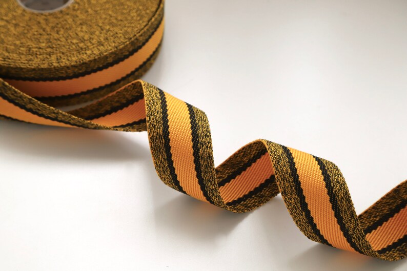 May include: A black and orange striped ribbon with a textured surface.