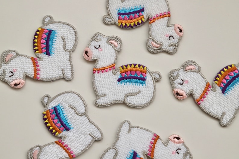 Puede incluir: Siete parches de llama bordados blancos con dise&ntilde;os geom&eacute;tricos coloridos. Las llamas est&aacute;n en varias poses, incluyendo de pie, sentadas y acostadas.