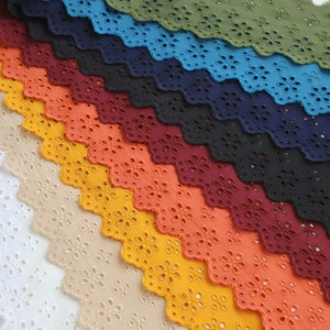 May include: A collection of 12 different colours of cotton eyelet lace trim. The lace is scalloped and has a delicate floral pattern. The colours range from white to dark green.