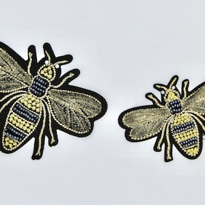 May include: Two embroidered bee patches, one larger than the other, with black outlines and gold and black bead details.