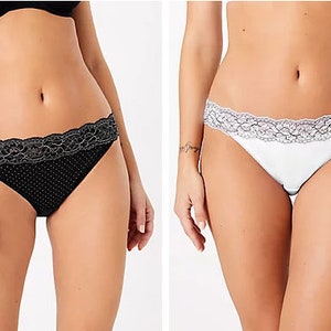 Puede incluir: Dos pares de ropa interior, uno negro con lunares blancos y otro blanco con encaje. Ambos pares tienen encaje.