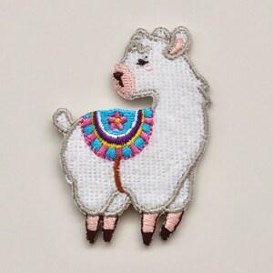 Puede incluir: Parche de llama blanco bordado con una silla de montar colorida. La llama est&aacute; de pie sobre cuatro patas y tiene la nariz y las orejas rosas.