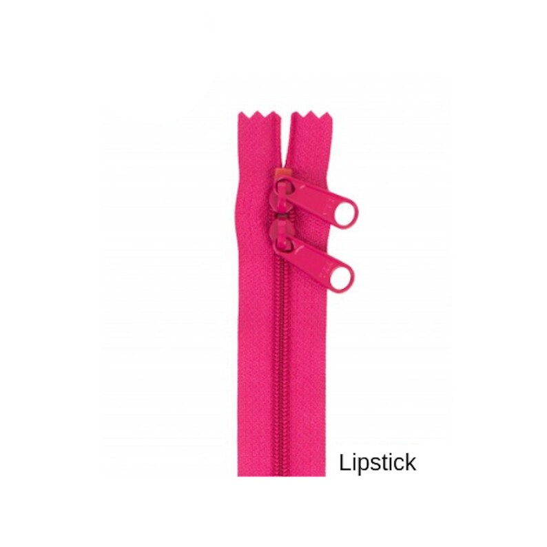 May include: A bright pink zipper with two metal sliders. The zipper is closed and the sliders are in the up position. The zipper is labeled "Lipstick".