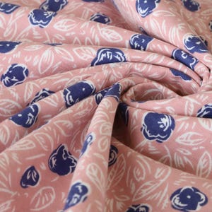 Peut inclure: Tissu rose avec un motif floral blanc et bleu. Le tissu est plié et montre le motif des deux côtés.