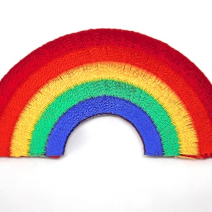 May include: An embroidered patch shaped like an arch, featuring a rainbow design. The patch is made from red, orange, yellow, green, blue and purple thread.