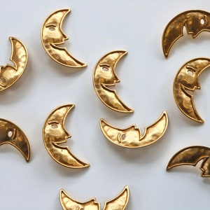 Puede incluir: Una colecci&oacute;n de 10 dijes de metal dorado en forma de media luna con un dise&ntilde;o de cara sonriente. Los dijes tienen una textura martillada y son perfectos para la elaboraci&oacute;n de joyas o manualidades.